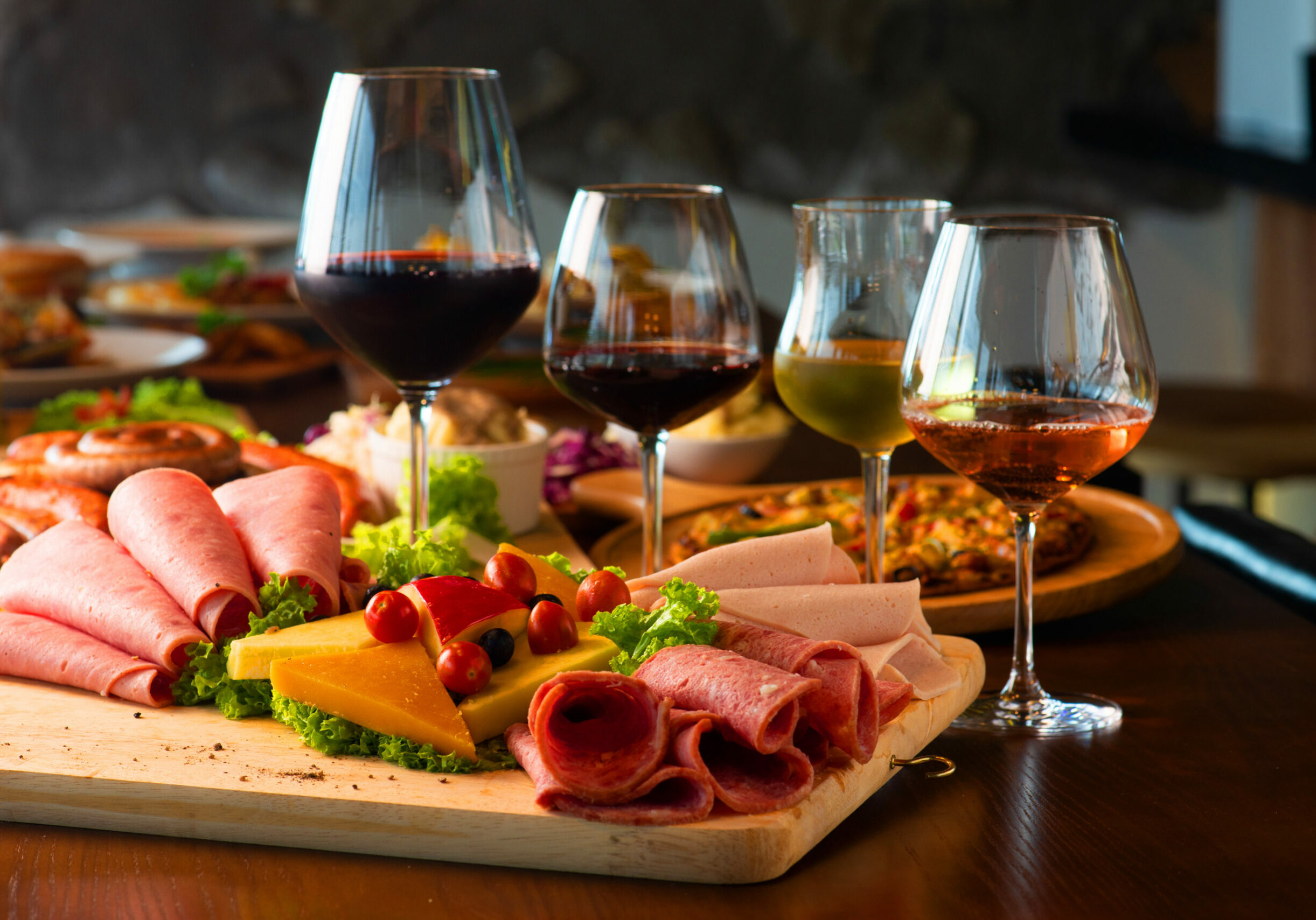 Antipasti platter with different meat and cheese products on wooden board